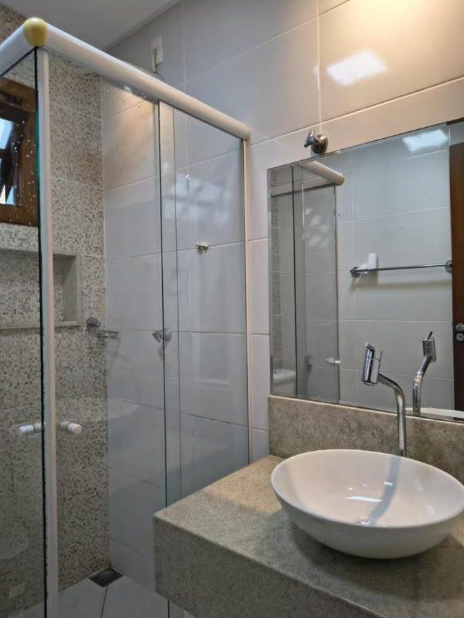 Banheiro com box de vidro e cuba de apoio
