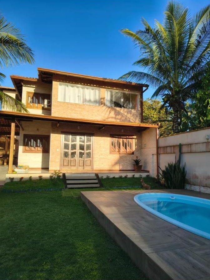 A casa duplex com quintal gramado e piscina, num dia de sol