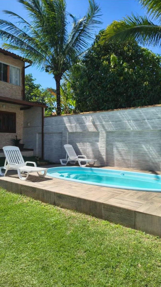 Piscina privativa com espreguiçadeiras, gramado e coqueiro